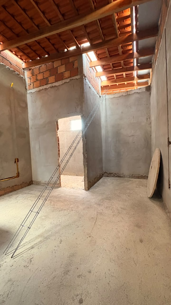 Sala em construção com armação de escada e paredes rebocadas
