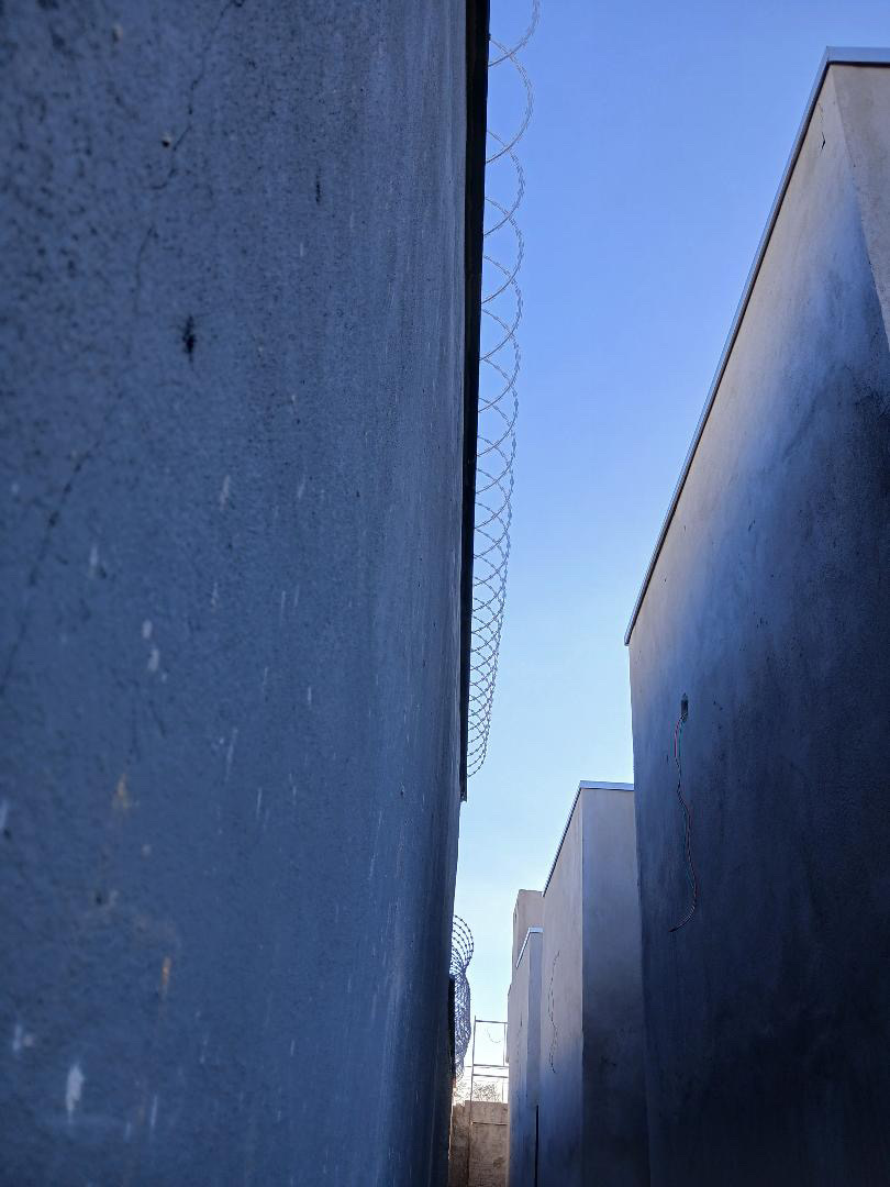 Lateral da casa com muro concluído e concertina instalada